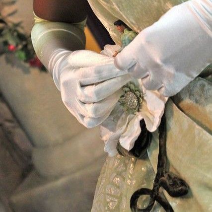 a close up of a person's hand wearing white gloves and holding an old pair of scissors