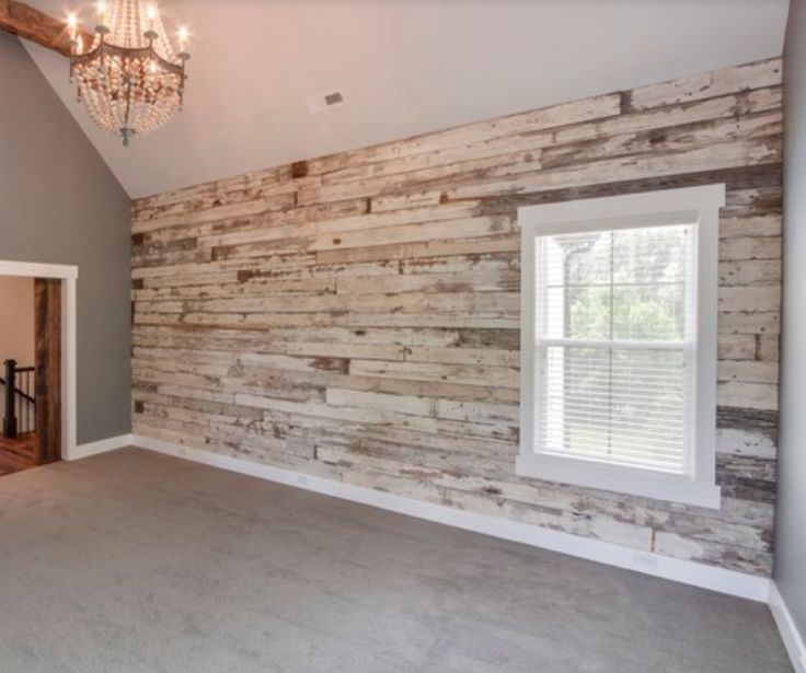 an empty room with a chandelier hanging from the ceiling and wood paneling on the walls