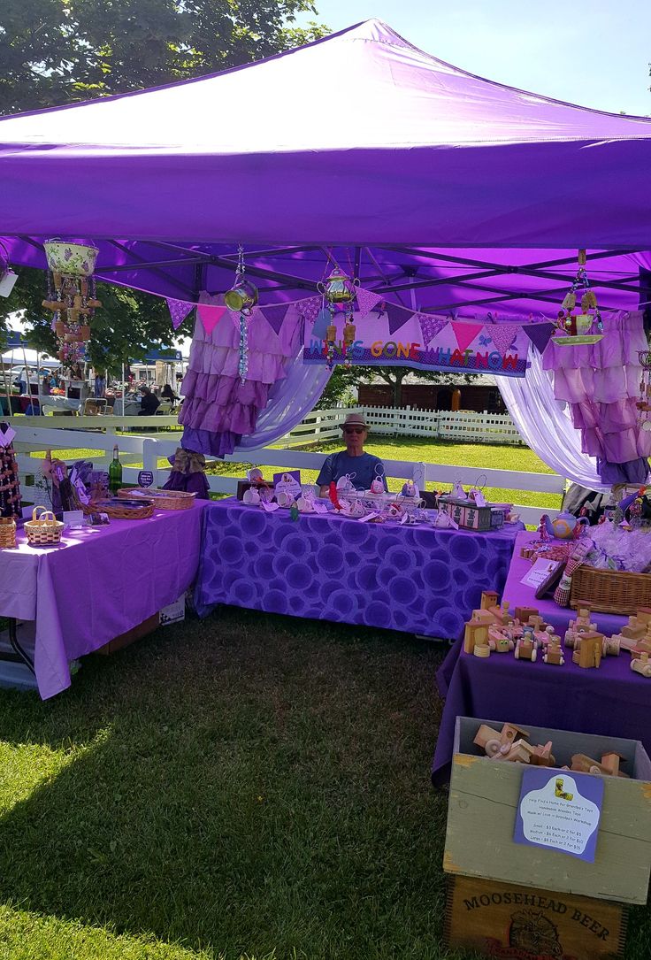 a purple tent is set up in the grass for an outdoor party with food and decorations