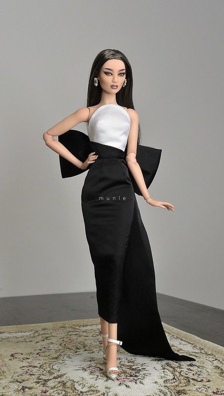 a barbie doll wearing a black and white dress on top of a carpeted area