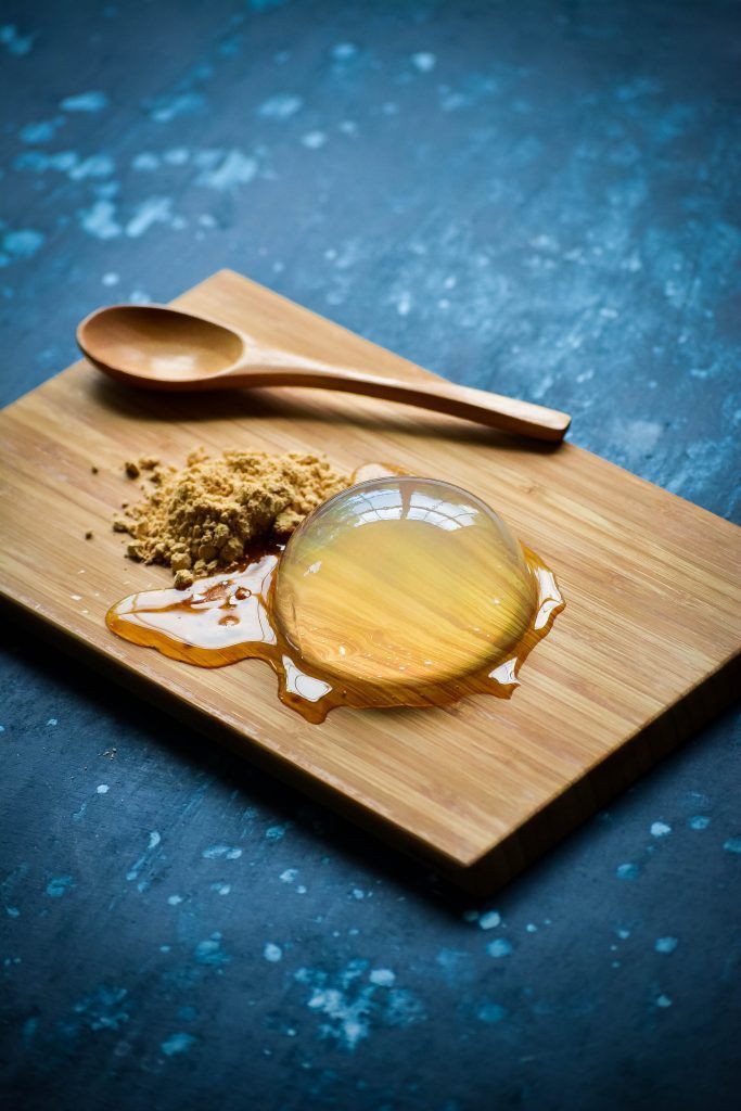 a wooden spoon sitting on top of a cutting board next to some liquid and spices