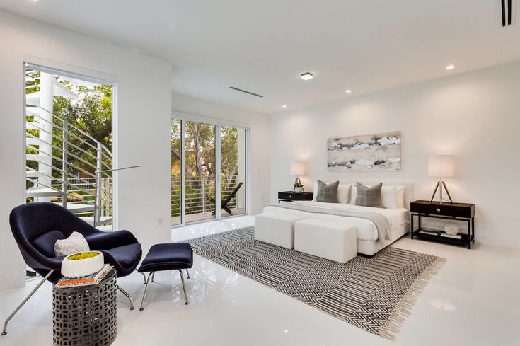 a bedroom with white walls and large windows