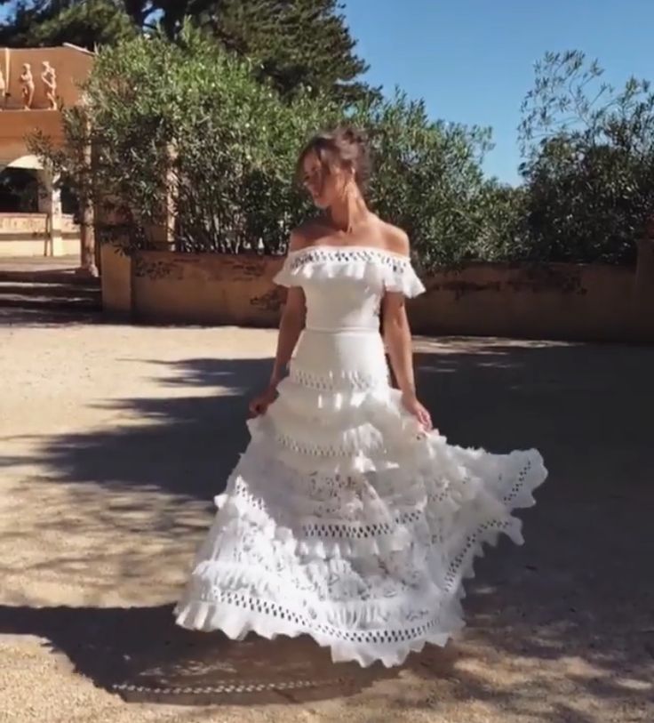 a woman in a white dress is walking down the street