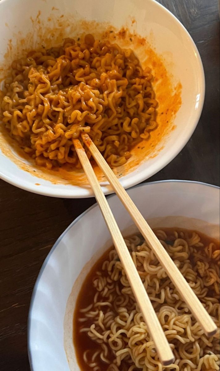 two bowls with noodles and chopsticks in them