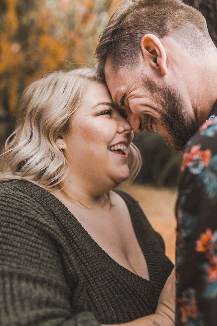 a man and woman laugh together in front of a tree