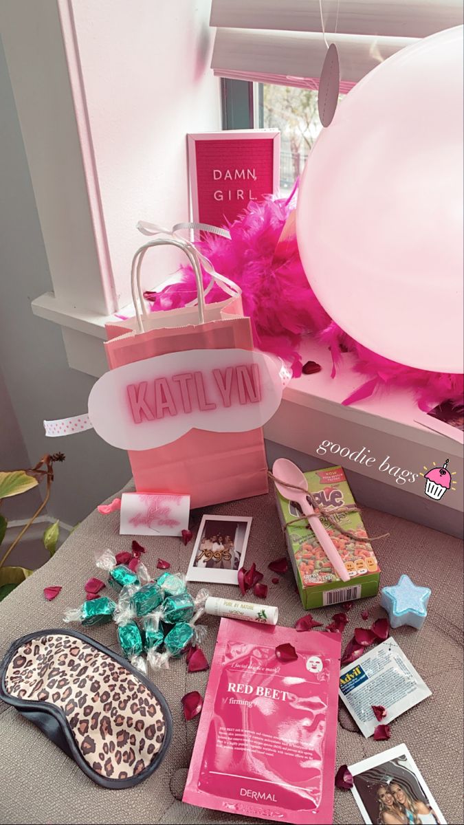 the contents of a pink gift bag and other items sit on a table in front of a window