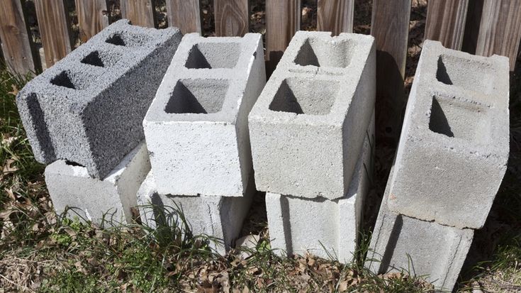 four cement blocks sitting next to each other on the ground in front of a fence