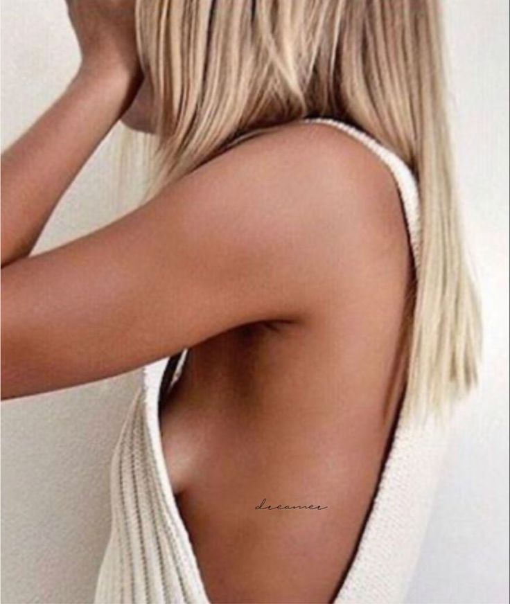 the back of a woman's white top with her hand on her shoulder and one arm behind her head