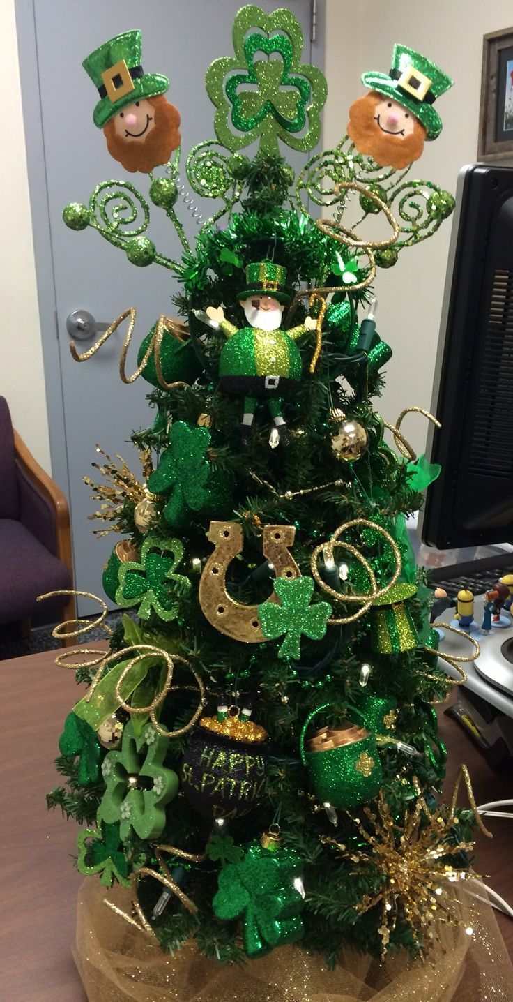 a green christmas tree decorated with shamrocks and gold trimmings in an office cubicle