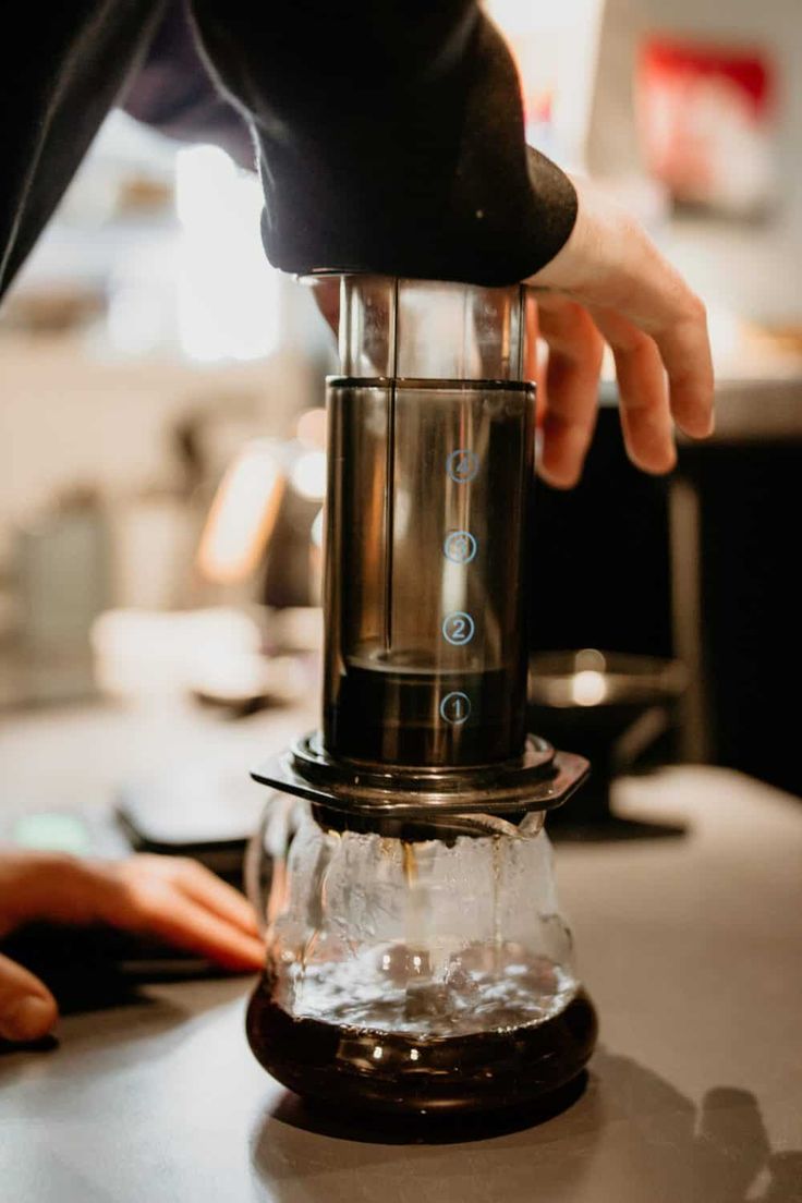 a person is pouring water into a coffee maker