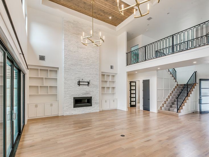 an empty living room with wood flooring and white walls, open staircase to the second floor