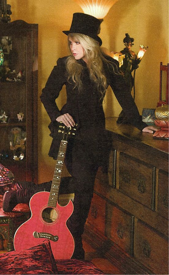 a woman standing next to a red guitar in a room filled with furniture and decorations