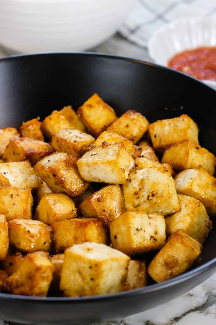 a pan filled with cooked tofu sitting on top of a counter next to sauce