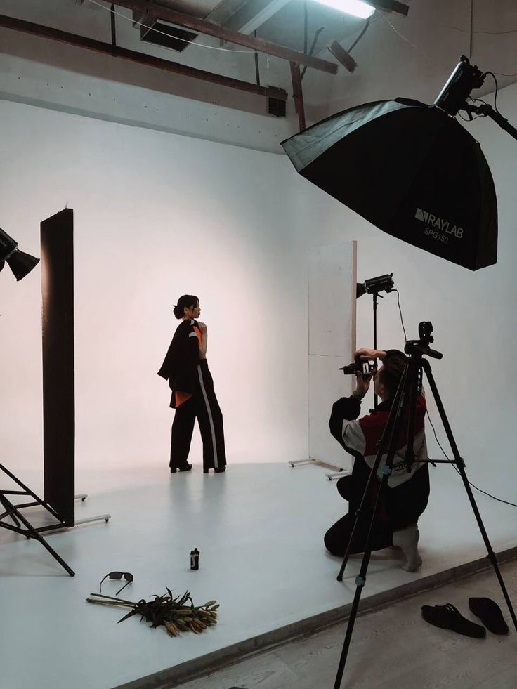 a woman is standing in the middle of a photo studio with her camera and lighting equipment