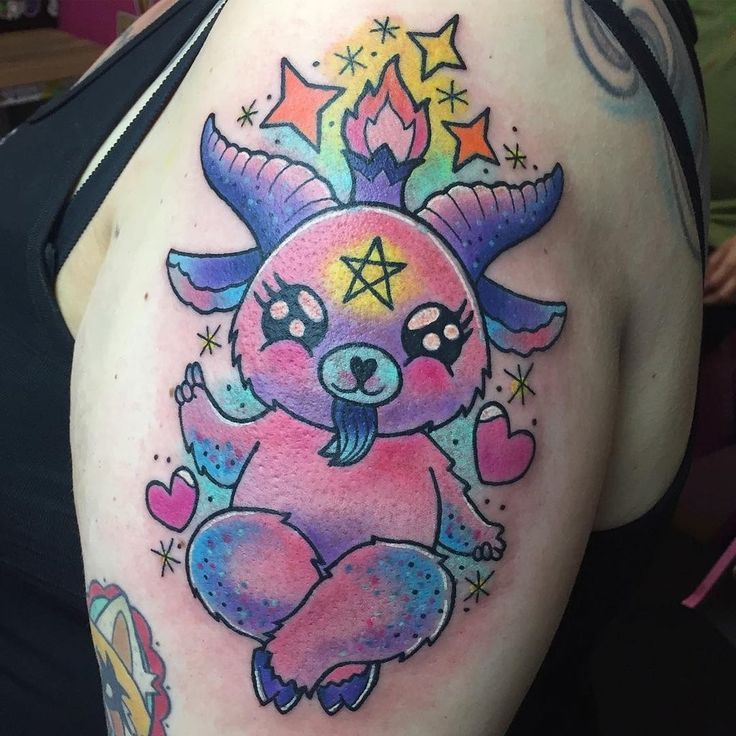 a woman with a tattoo on her shoulder has a pink bear and stars around it