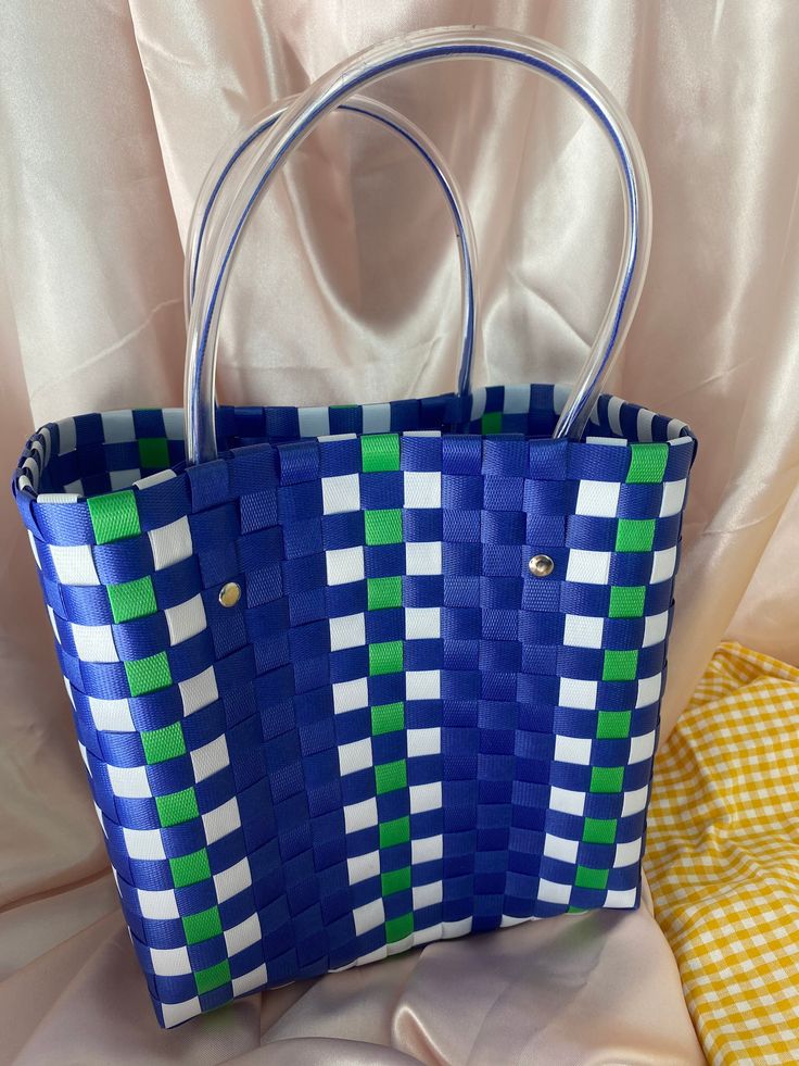 a blue and green handbag sitting on top of a white cloth covered tablecloth