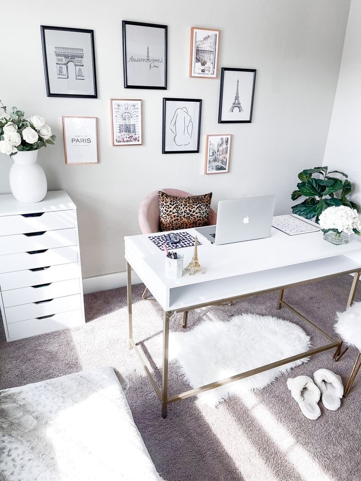 a white desk topped with a laptop computer on top of a white table surrounded by pictures