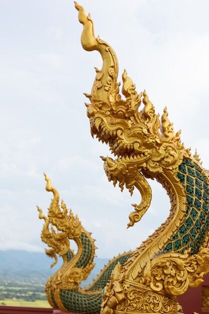 a golden dragon statue sitting on top of a red wall next to a green roof