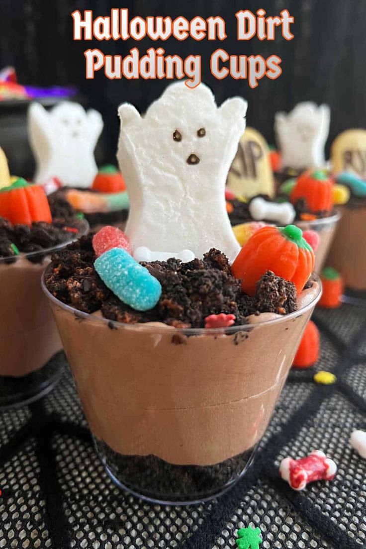 halloween dirt pudding cups with marshmallows and candy in the middle on a table