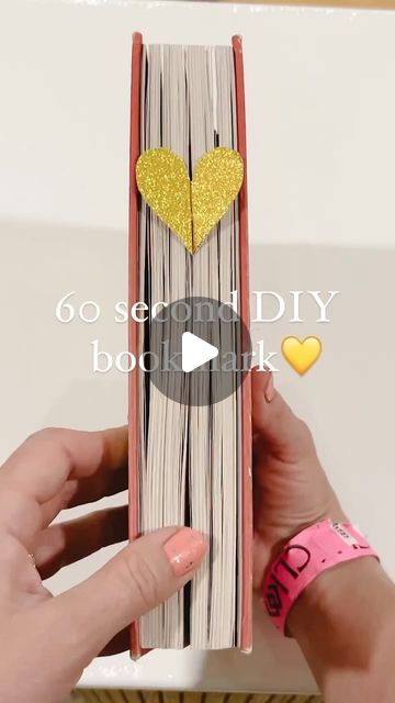 someone is holding up an origami book with gold hearts on the front and back