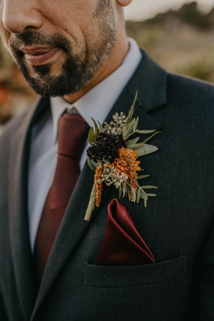 a man wearing a suit and tie with a boutonniere on his lapel