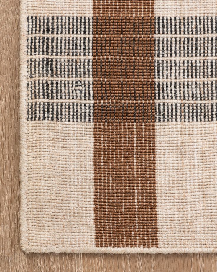 a brown and white checkered rug on top of a wooden floor next to a wall