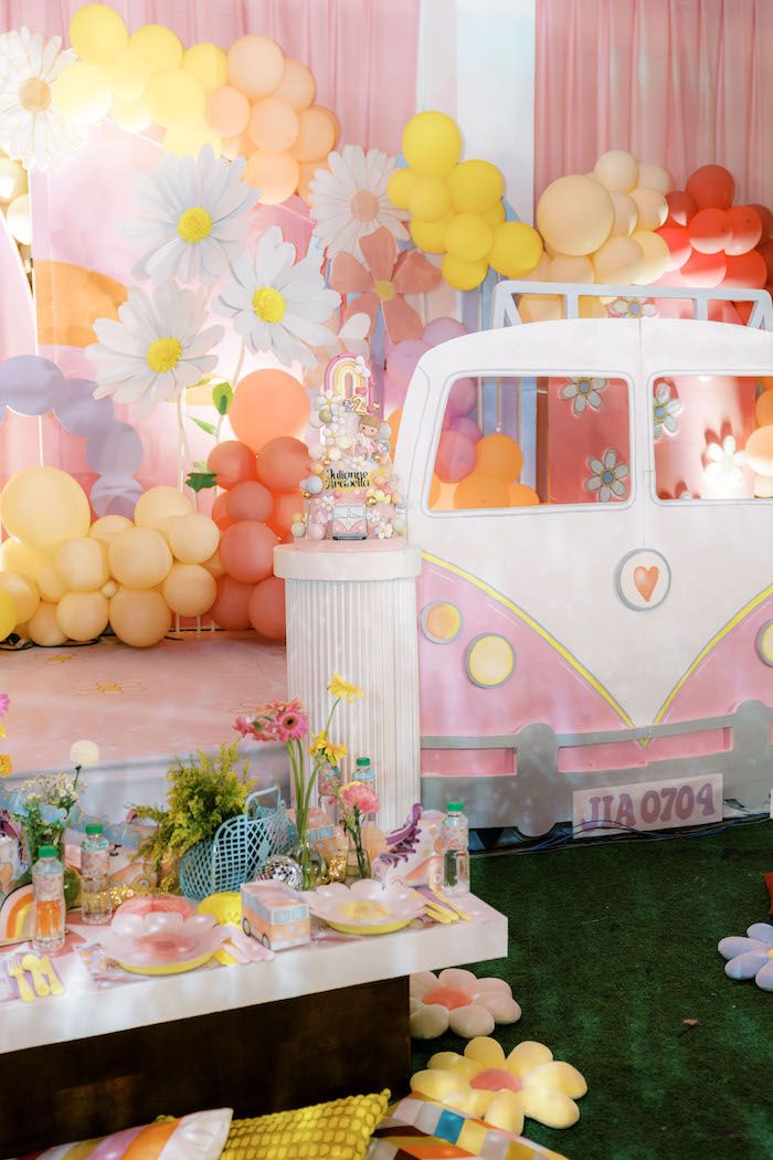 a pink and white vw camper parked in front of balloons