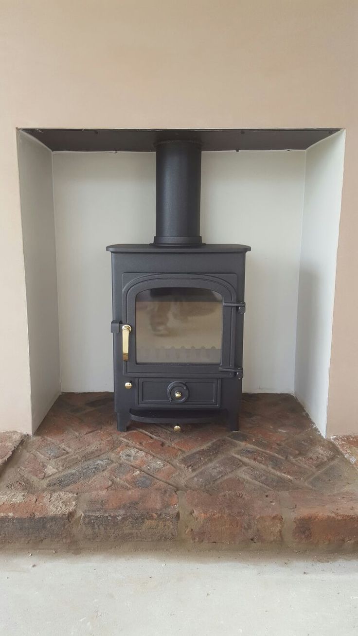 a wood burning stove sitting inside of a room next to a brick floor and wall