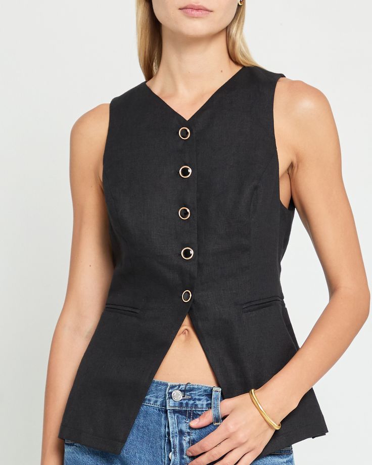 Product Details The Annabel Top is a must-have for any fashion-forward individual. With its elegant gold and black enamel buttons, this top exudes sophistication and style. The back buckle allows for a customizable fit, making it both chic and fitted. Elevate your wardrobe with this versatile piece. - Front buttons- Lined- Content: Fabric: 100% Linen; Lining: 100% Rayon Style# K24WTPF1242G Fit Notes - Model wearing a size 2- Model measurements: 5'10'' Height / 32'' Bust / 24'' Waist / 34'' Hips- Fitted Black Tops With Back Button Closure, Black Top With Button Closure And Collared Neckline, Luxury Black Top With Hidden Button Closure, Black Sleeveless Tank Top With Button Closure, Black V-neck Vest With Button Closure, Dress Vest, Linen Top, Vest Dress, Black Enamel