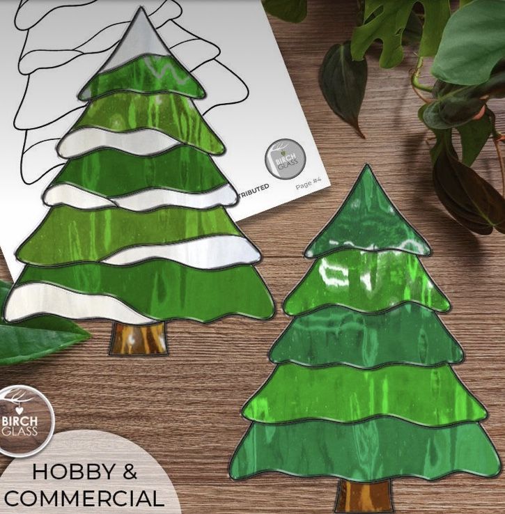 two green christmas trees cut out from paper on a wooden table