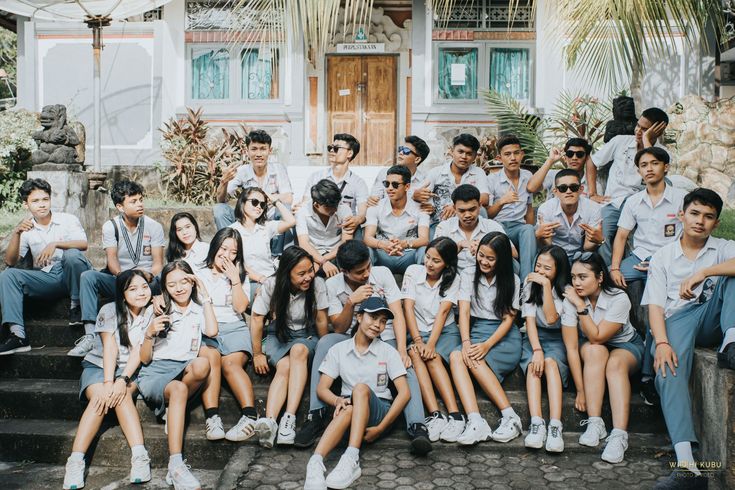 a group of young people posing for a photo in front of a house with palm trees