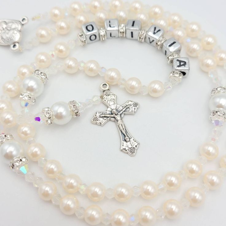 Elegant and personalised Rosary beads made with cream beads for Hail Mary & white beads for Our Father with a dainty and small sized crucifix. Beautiful gift for many occasions such as a christening, first holy communion, baptism, confirmation and much more! Add a name and/or Saint pendant to personalise and choose your own centrepiece with a wide variety available. Please select whether you would like to a add name on the rosary from drop down menu then choose the centrepiece you would like as Personalized White Baptism Dress, White Pearl Rosary For Baptism, Adjustable White Rosary For First Communion, Personalized White Rosary For Confirmation, White Rosary With Round Beads For Confirmation, Personalized Rosary With Round Beads For Baptism, Customizable White Jewelry For Baptism, Handmade White Rosary For Baptism, Personalized White Rosary