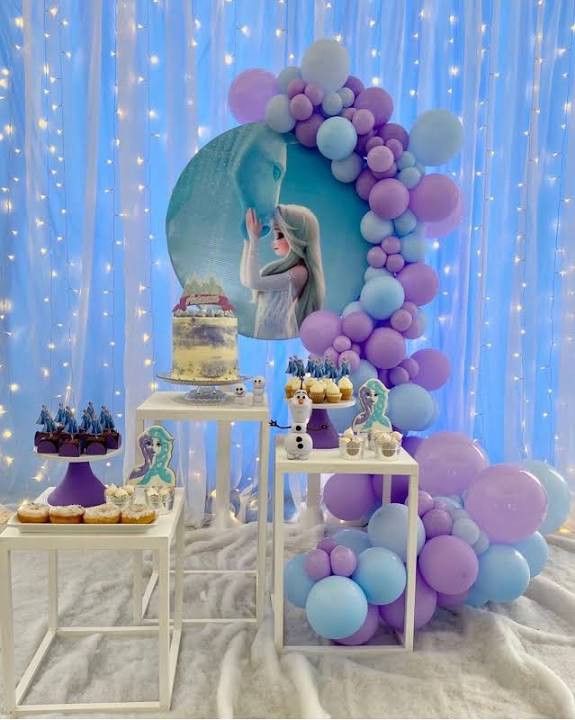 a table with cake, cupcakes and balloons in front of a blue backdrop