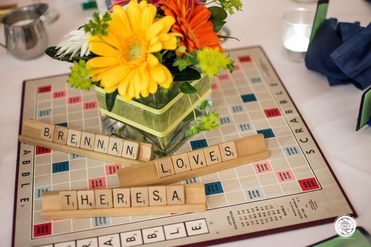 a vase filled with flowers sitting on top of a board game table covered in scrabble tiles