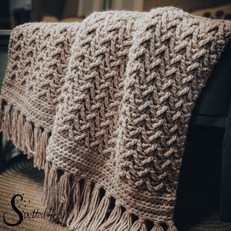 two knitted blankets sitting on top of a chair