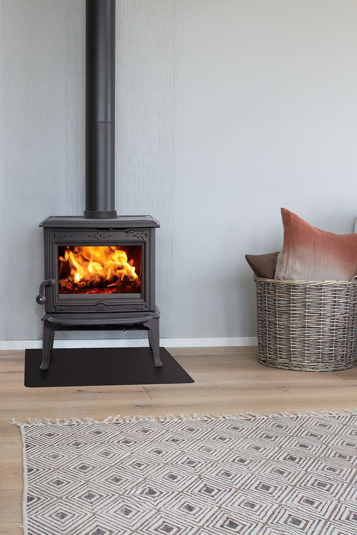 Jøtul F 100 SE black cast iron wood stove, in a grey kitchen, with light wooden floors and a carpet. Corner Log Burner, Wood Stove Installation, Flat Top Stove, Small Wood Burning Stove, Small Wood Stove, Nordic Aesthetic, Multi Fuel Stove, Living Room Red, Log Burner