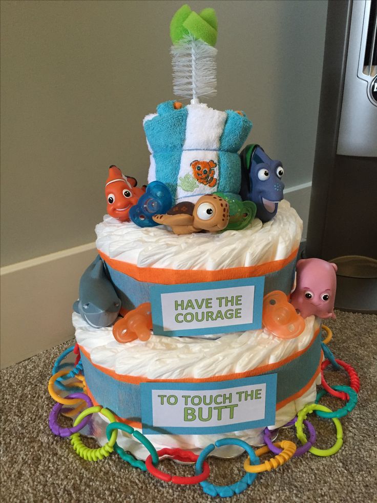 a diaper cake that has been decorated with toys and words on the bottom layer