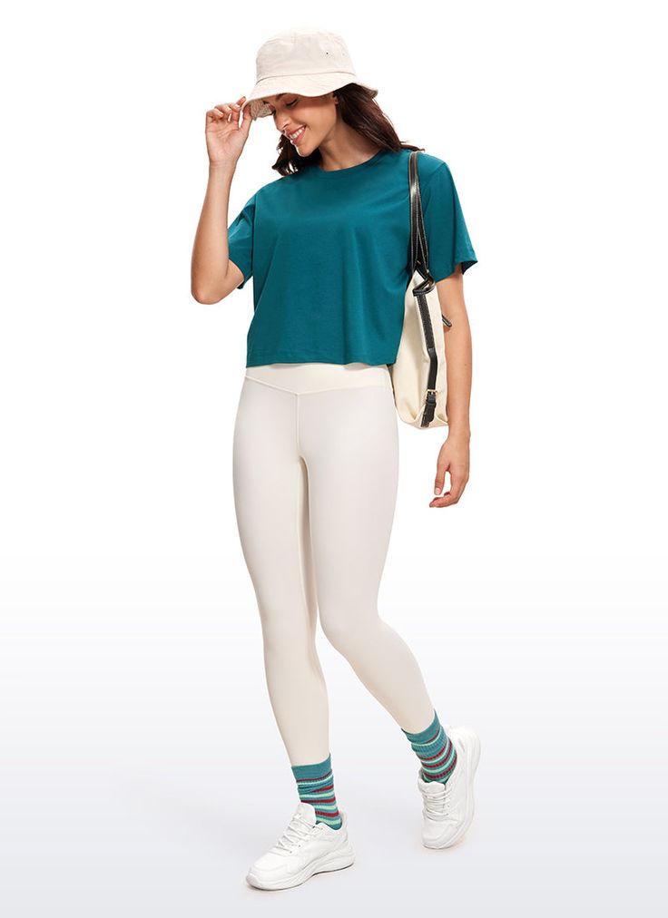 a woman wearing white pants and a teal top