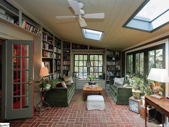 a living room filled with lots of furniture next to a window covered in bookshelves