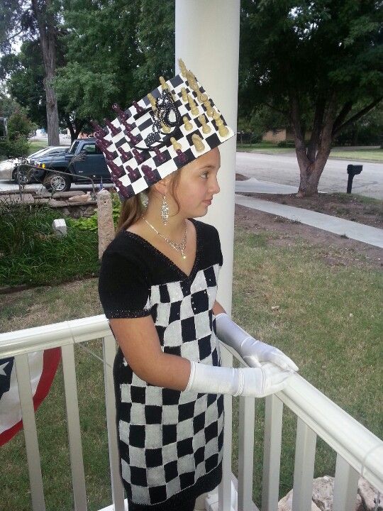 a woman in a black and white dress is standing on a porch with a checkered hat