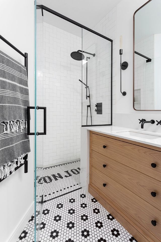 a bathroom with black and white tile flooring, wooden cabinets and a large mirror