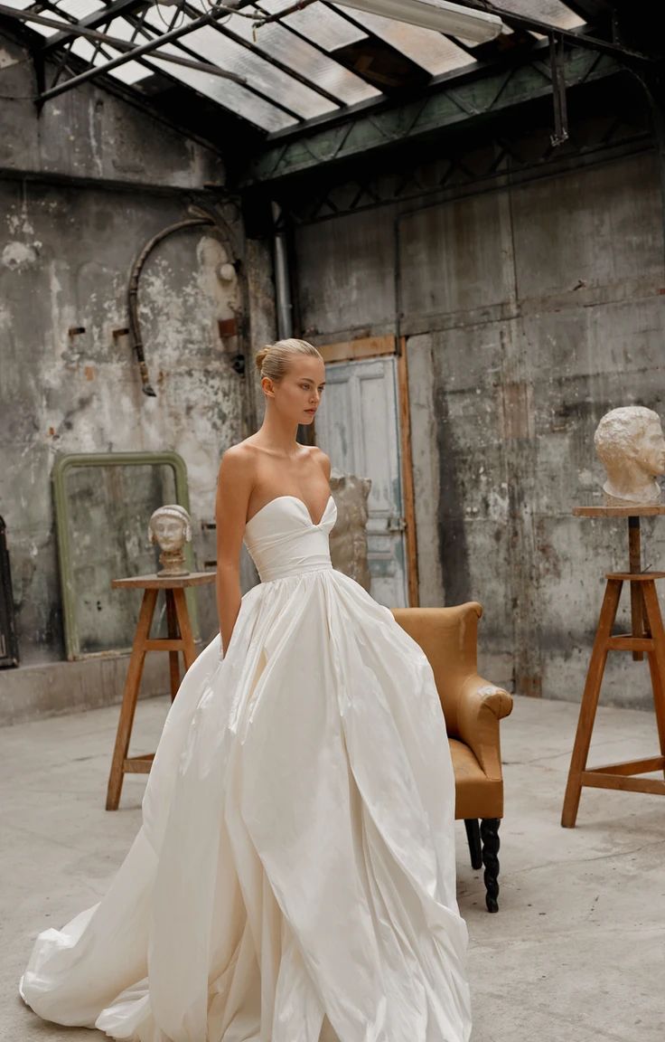 a woman in a white wedding dress standing next to a chair