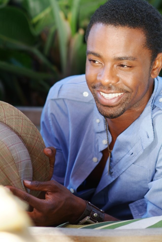 a man is smiling while holding a hat