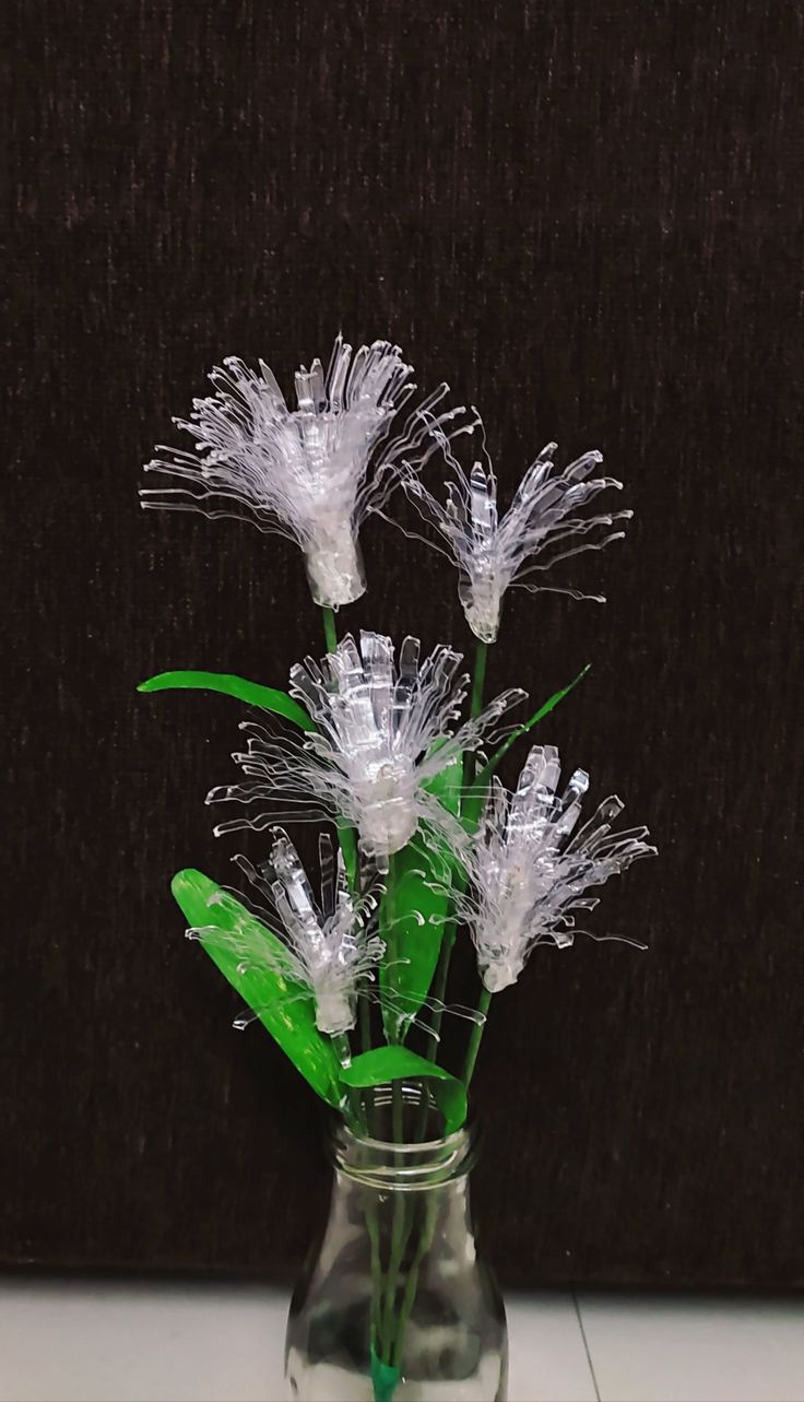 some flowers are in a glass vase on the table with water and plastic wrap around them