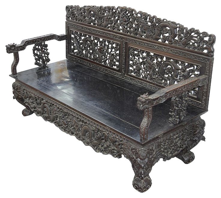 an ornate wooden bench sitting on top of a white floor next to a metal shelf