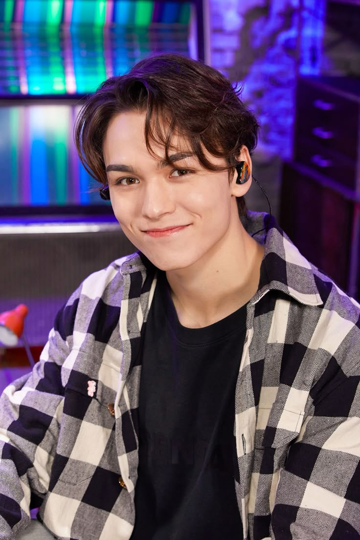 a young man is sitting in front of a tv set and smiling at the camera