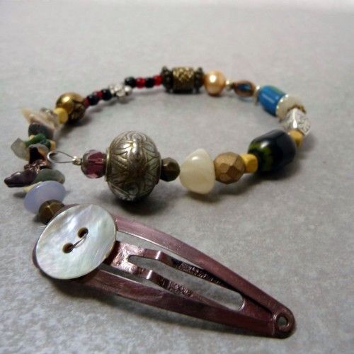 a close up of a hair clip and some beads on a table with a button