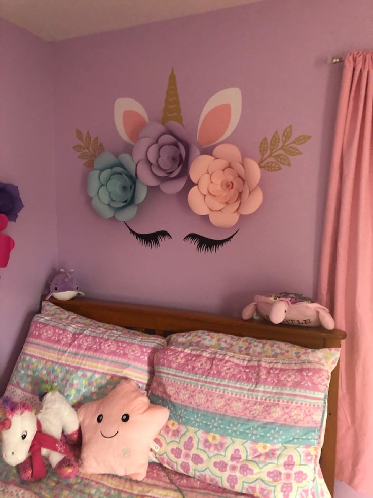 a child's bedroom decorated in pink, purple and green with unicorns on the wall