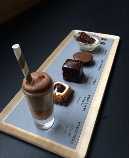 there is a tray with different types of desserts on it and a drink in the glass