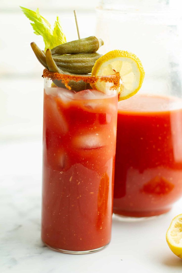 two glasses filled with red liquid and garnished with lemon